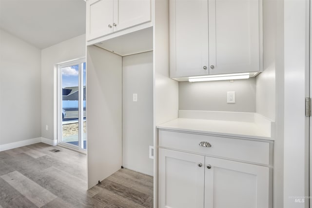 kitchen with light hardwood / wood-style floors and white cabinetry