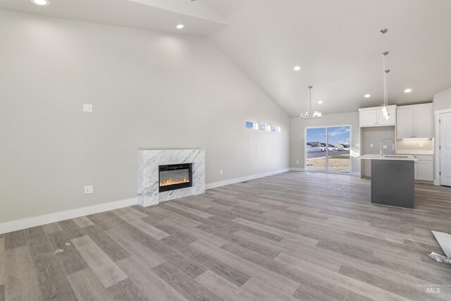 unfurnished living room featuring light hardwood / wood-style floors, a chandelier, sink, and a premium fireplace