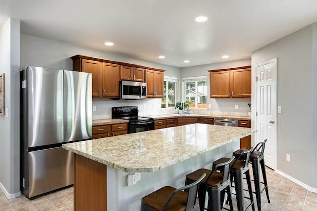 5375 N Isla Ave, Meridian, ID 83646 - kitchen featuring appliances with stainless steel finishes, baseboards, a kitchen island, a kitchen bar, and brown cabinetry