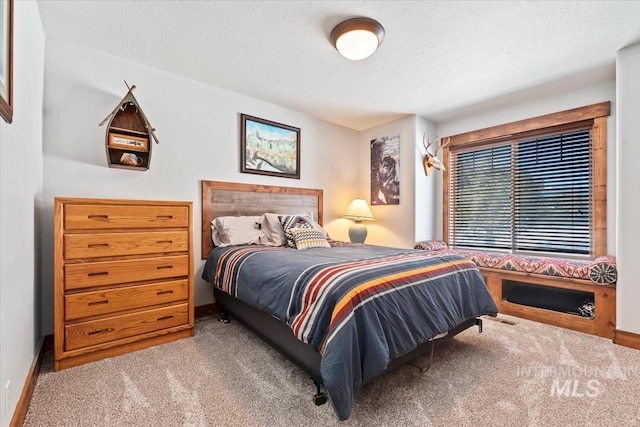 bedroom featuring light colored carpet and a textured ceiling