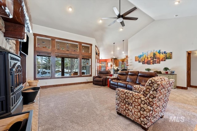 living room with ceiling fan, a wood stove, light colored carpet, and high vaulted ceiling