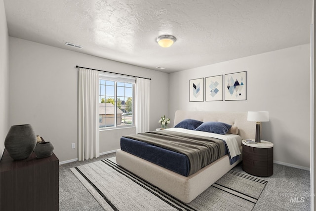 bedroom with light colored carpet and a textured ceiling