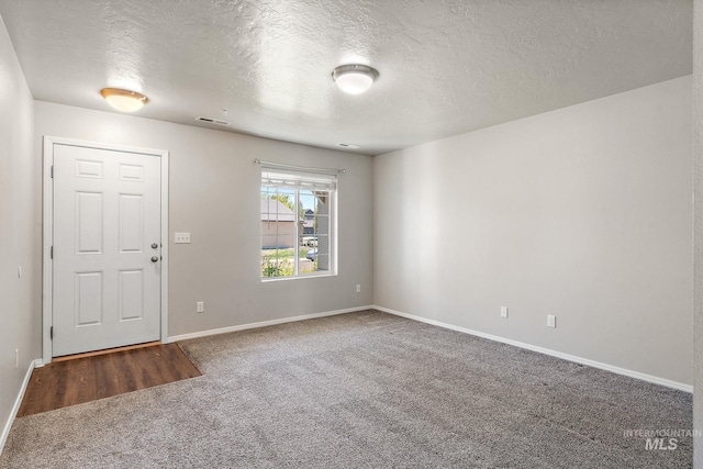 carpeted foyer entrance with a textured ceiling