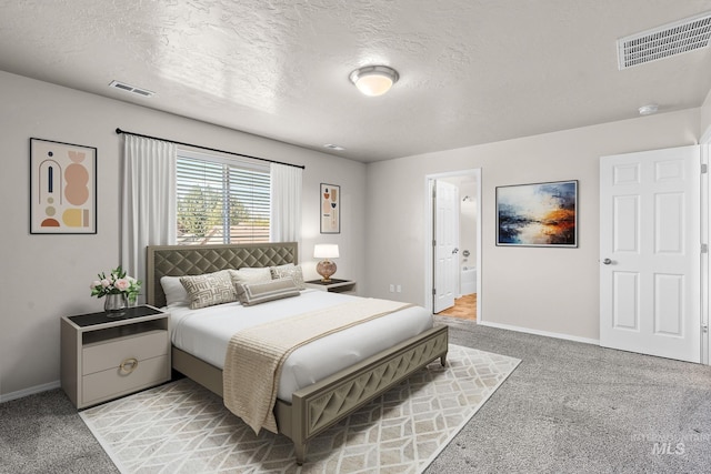 carpeted bedroom featuring ensuite bath and a textured ceiling