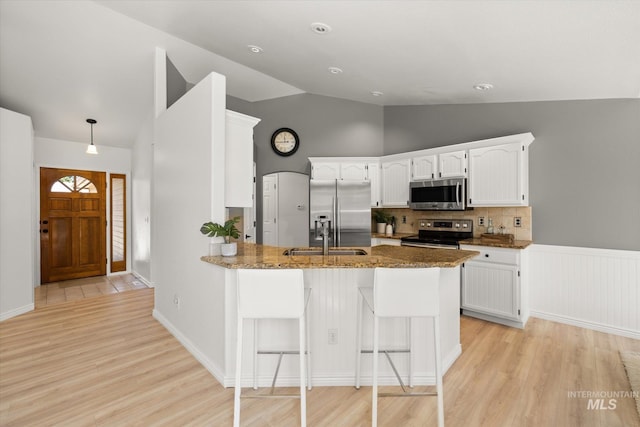 512 S Pelican Way, Meridian, ID 83642 - kitchen featuring appliances with stainless steel finishes, a peninsula, dark stone counters, light wood finished floors, and high vaulted ceiling
