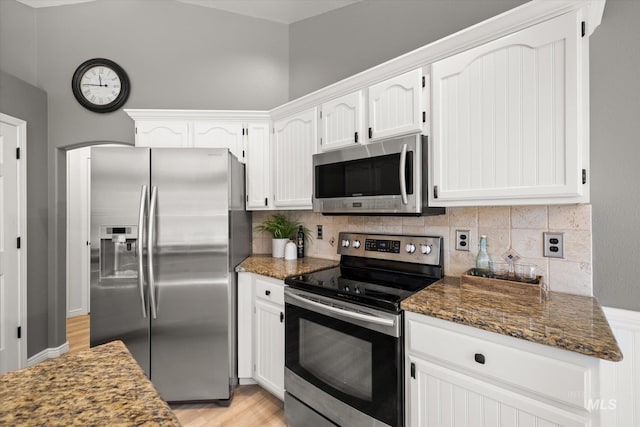 512 S Pelican Way, Meridian, ID 83642 - kitchen featuring appliances with stainless steel finishes, white cabinetry, tasteful backsplash, dark stone countertops, and light wood-style flooring