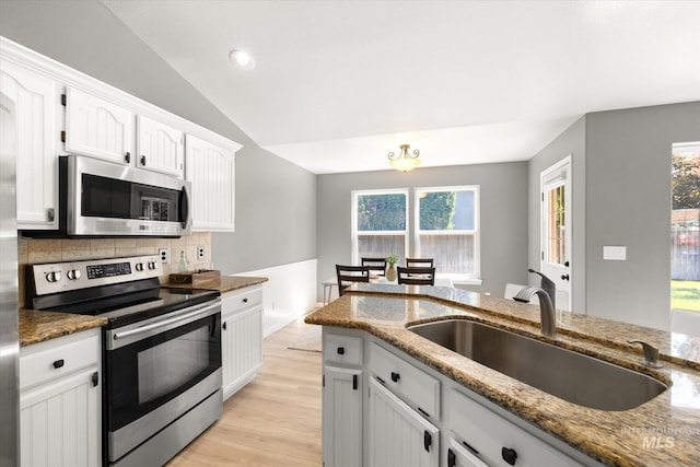 512 S Pelican Way, Meridian, ID 83642 - kitchen with appliances with stainless steel finishes, a sink, light wood-style flooring, decorative backsplash, and white cabinetry
