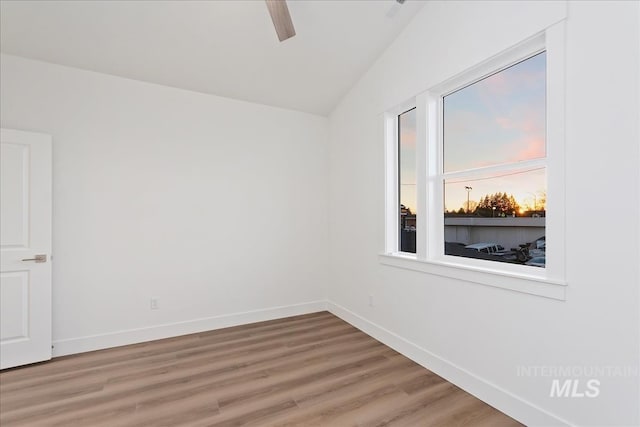 spare room featuring wood-type flooring and vaulted ceiling