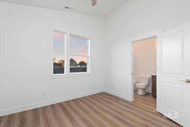 unfurnished bedroom featuring ensuite bathroom and wood-type flooring