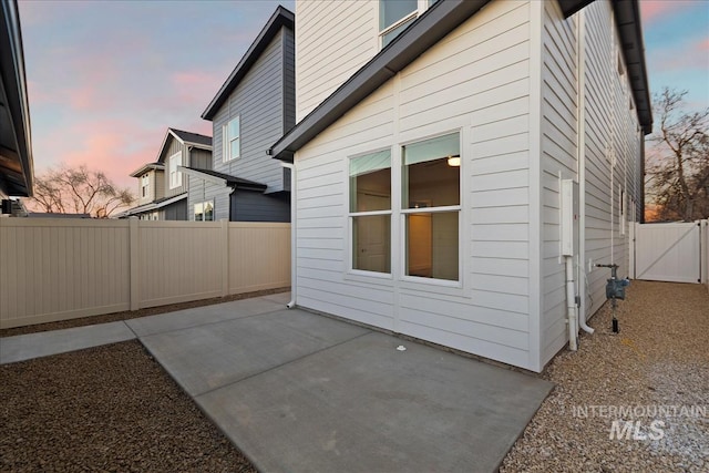 property exterior at dusk featuring a patio area