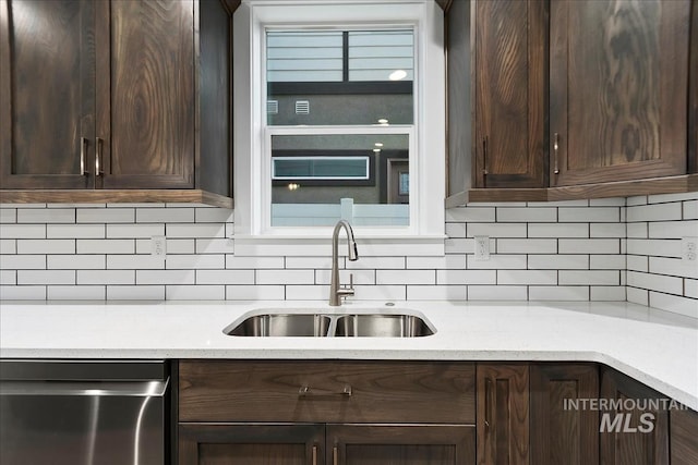 kitchen with sink, backsplash, light stone counters, dark brown cabinetry, and stainless steel dishwasher