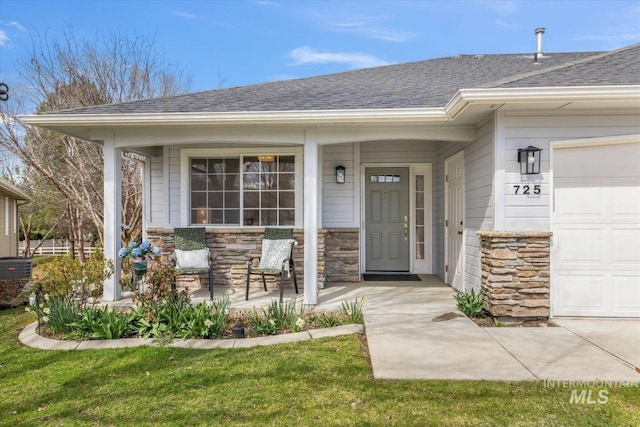 entrance to property featuring a garage, a yard, and covered porch