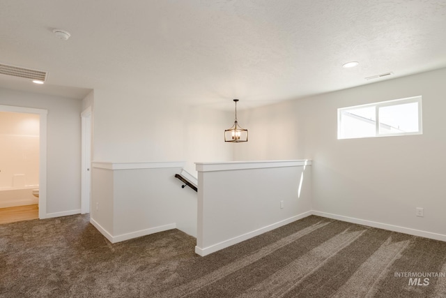 interior space with carpet, a textured ceiling, visible vents, and baseboards