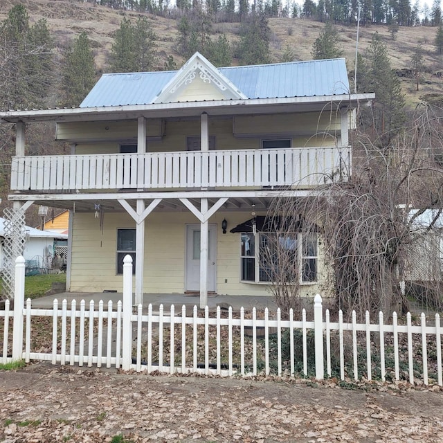 view of front of property featuring a fenced front yard, a porch, metal roof, and a balcony