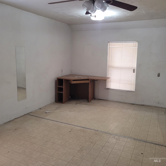 empty room with a ceiling fan, light floors, and a textured ceiling