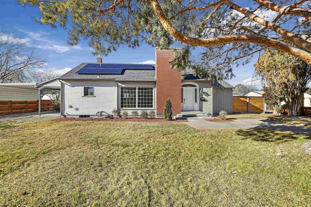 back of property featuring a yard and solar panels