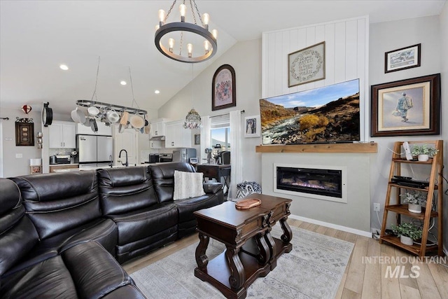 1440 Riverbend Pl, Twin Falls, ID 83301 - living room featuring a chandelier, a glass covered fireplace, light wood-style flooring, high vaulted ceiling, and recessed lighting