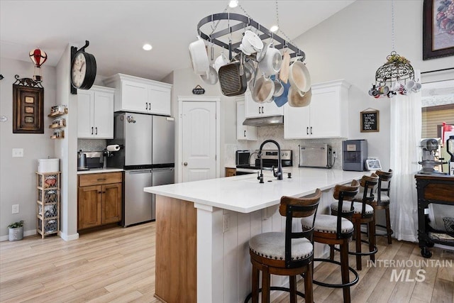 1440 Riverbend Pl, Twin Falls, ID 83301 - kitchen with freestanding refrigerator, a peninsula, light wood-type flooring, tasteful backsplash, and light countertops