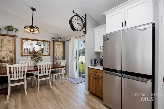 1440 Riverbend Pl, Twin Falls, ID 83301 - kitchen with freestanding refrigerator, lofted ceiling, light wood-style flooring, white cabinetry, and hanging light fixtures