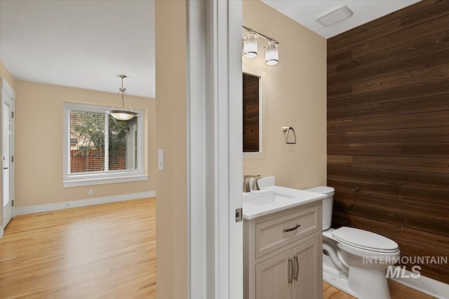 bathroom featuring toilet, wood finished floors, vanity, and baseboards