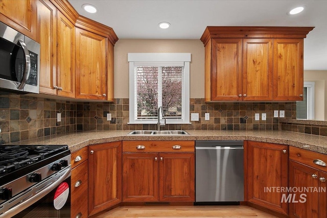 kitchen featuring brown cabinetry, tile countertops, a sink, and appliances with stainless steel finishes