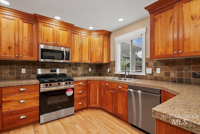 kitchen featuring brown cabinetry, a sink, and appliances with stainless steel finishes