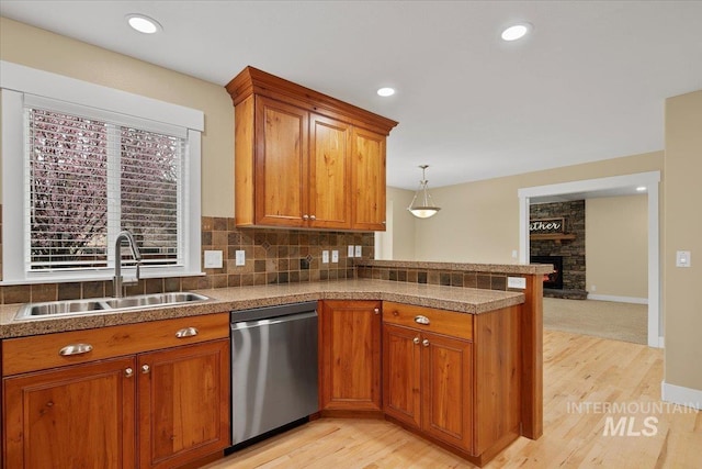kitchen featuring a sink, stainless steel dishwasher, a peninsula, and brown cabinets