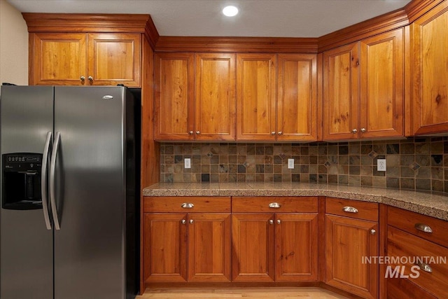 kitchen featuring brown cabinetry, tasteful backsplash, tile countertops, and stainless steel refrigerator with ice dispenser