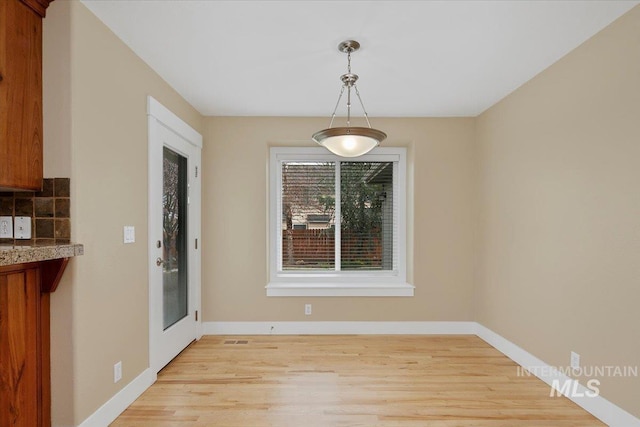 unfurnished dining area featuring light wood finished floors and baseboards