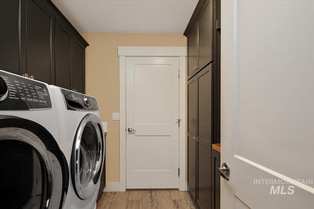 clothes washing area featuring cabinet space, washer and clothes dryer, and light wood-style flooring