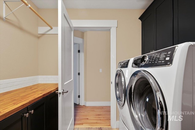 laundry room with light wood-type flooring, washing machine and clothes dryer, and cabinet space