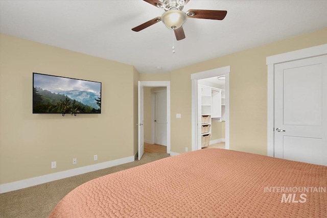 bedroom featuring a closet, light colored carpet, a ceiling fan, a spacious closet, and baseboards