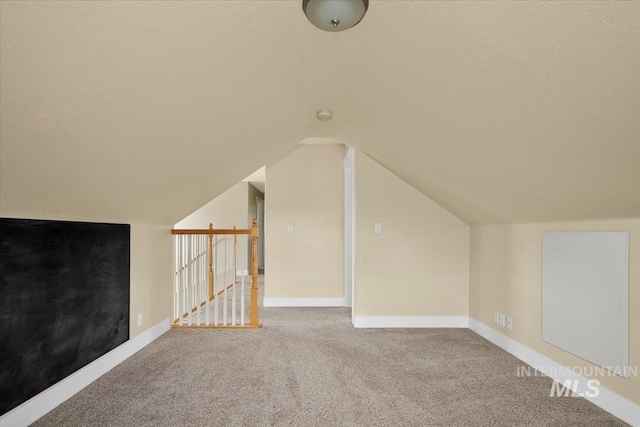 bonus room featuring carpet, baseboards, vaulted ceiling, and a textured ceiling