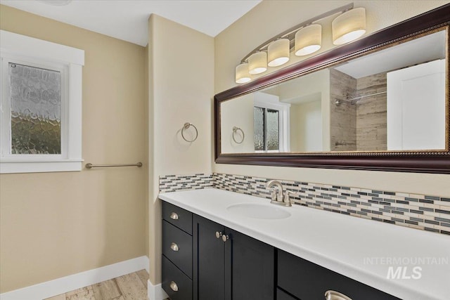 full bath with tiled shower, vanity, wood finished floors, decorative backsplash, and baseboards