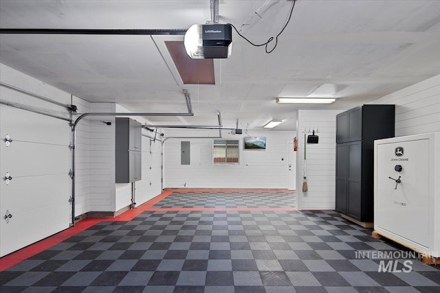 garage featuring a garage door opener, wooden walls, and electric panel
