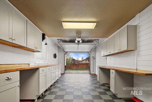 kitchen featuring a textured ceiling, wood counters, wood walls, and dark floors