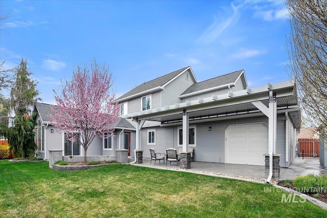back of property with a garage, a patio area, fence, and a lawn