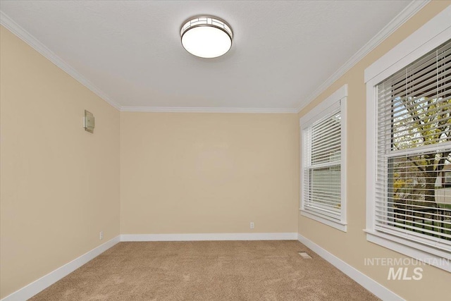 spare room featuring crown molding, carpet floors, baseboards, and visible vents