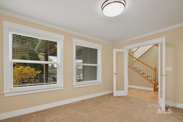 carpeted spare room featuring crown molding, visible vents, stairway, french doors, and baseboards