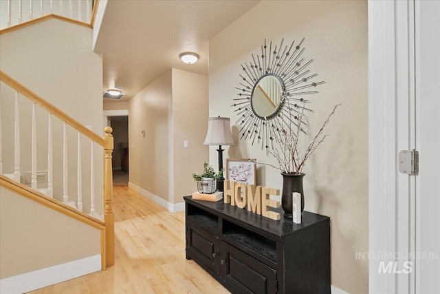 interior space with light wood-style flooring, baseboards, and stairway
