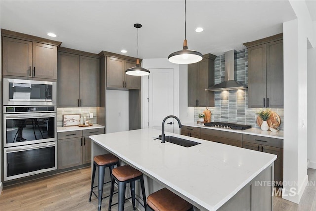 7779 W Daybreak Run Ct, Meridian, ID 83646 - kitchen featuring wall chimney exhaust hood, a sink, stainless steel appliances, decorative backsplash, and light wood-type flooring