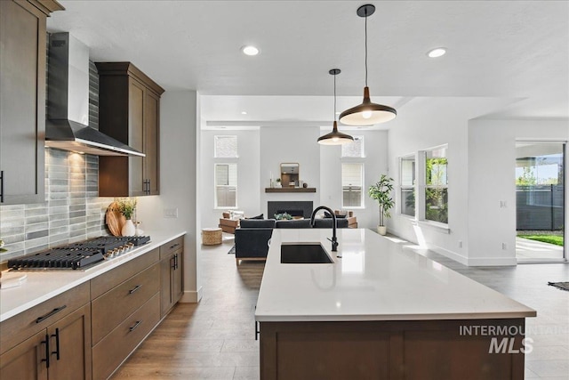 7779 W Daybreak Run Ct, Meridian, ID 83646 - kitchen with wall chimney range hood, a sink, stainless steel gas cooktop, open floor plan, and a center island with sink