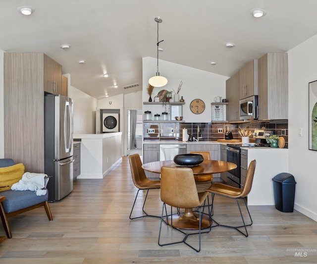 1681 W Idaho St, Boise, ID 83702 - dining space featuring vaulted ceiling, visible vents, light wood-style floors, stacked washing maching and dryer, and baseboards