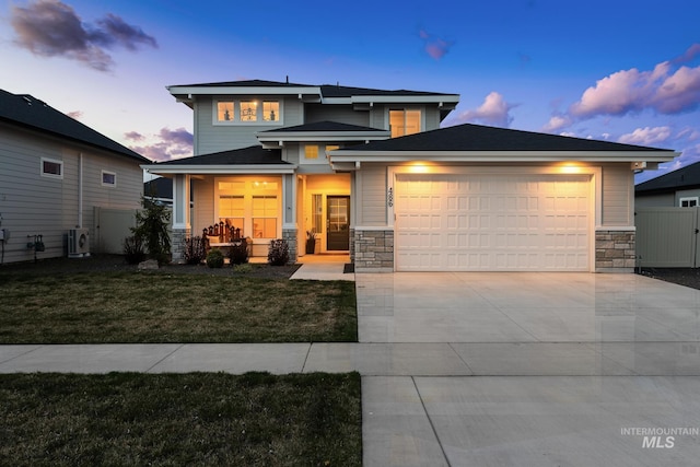 486 E Andes Dr, Kuna, ID 83634 - prairie-style home featuring a porch, a front yard, fence, stone siding, and an attached garage