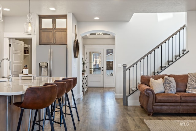 486 E Andes Dr, Kuna, ID 83634 - kitchen with glass insert cabinets, a kitchen bar, arched walkways, stainless steel refrigerator with ice dispenser, and wood finished floors