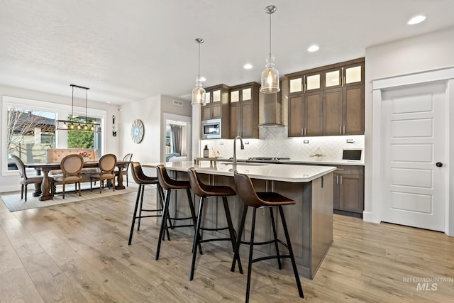 486 E Andes Dr, Kuna, ID 83634 - kitchen featuring dark brown cabinetry, a kitchen bar, stainless steel microwave, light countertops, and backsplash