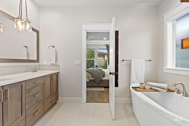 486 E Andes Dr, Kuna, ID 83634 - bathroom featuring a freestanding tub, baseboards, double vanity, backsplash, and connected bathroom