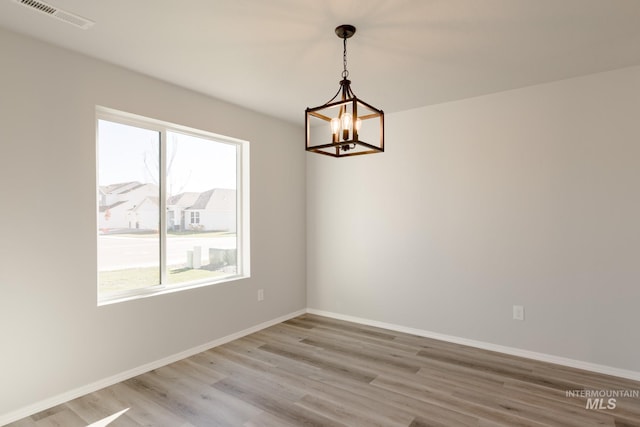 310 Chalcedony Ave, Caldwell, ID 83605 - empty room with baseboards, a notable chandelier, visible vents, and light wood-style floors
