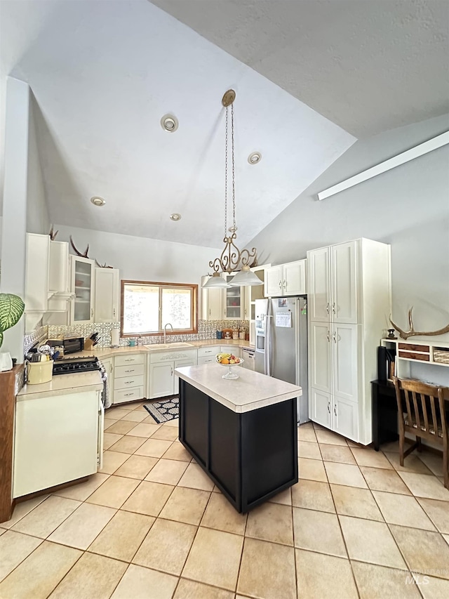 kitchen with a kitchen island, light tile patterned flooring, a sink, light countertops, and appliances with stainless steel finishes