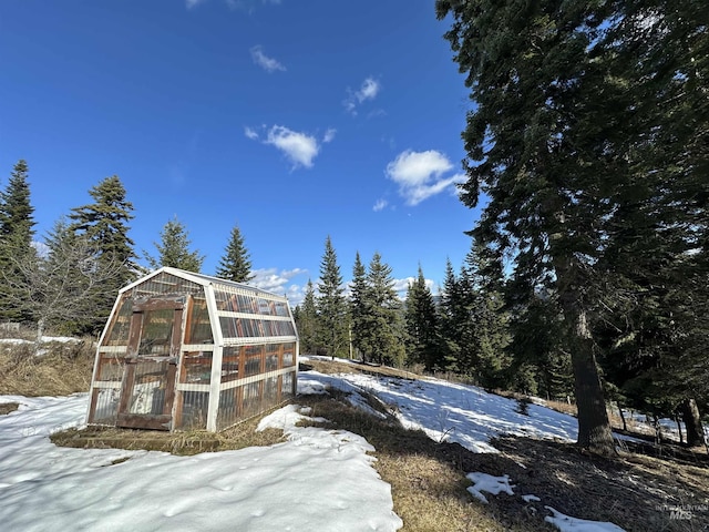 snow covered structure with an outbuilding and a greenhouse